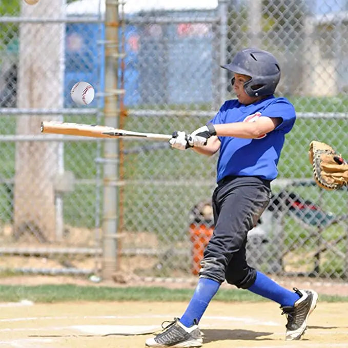 White baseball with red stitching in flight near a youth batter