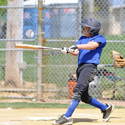 White baseball with red stitching in flight near a youth batter