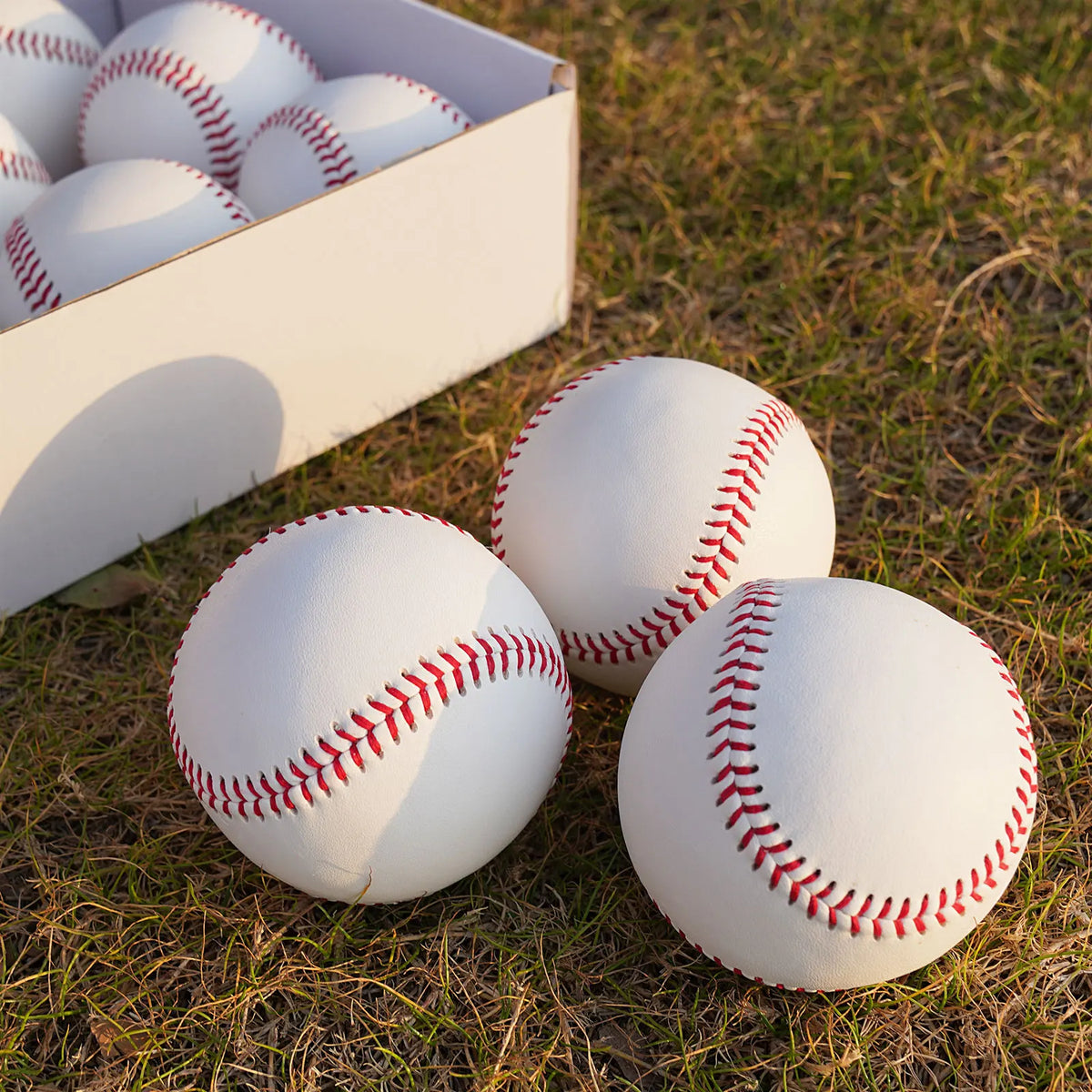 Three white baseballs with red stitched seams shown in an open box