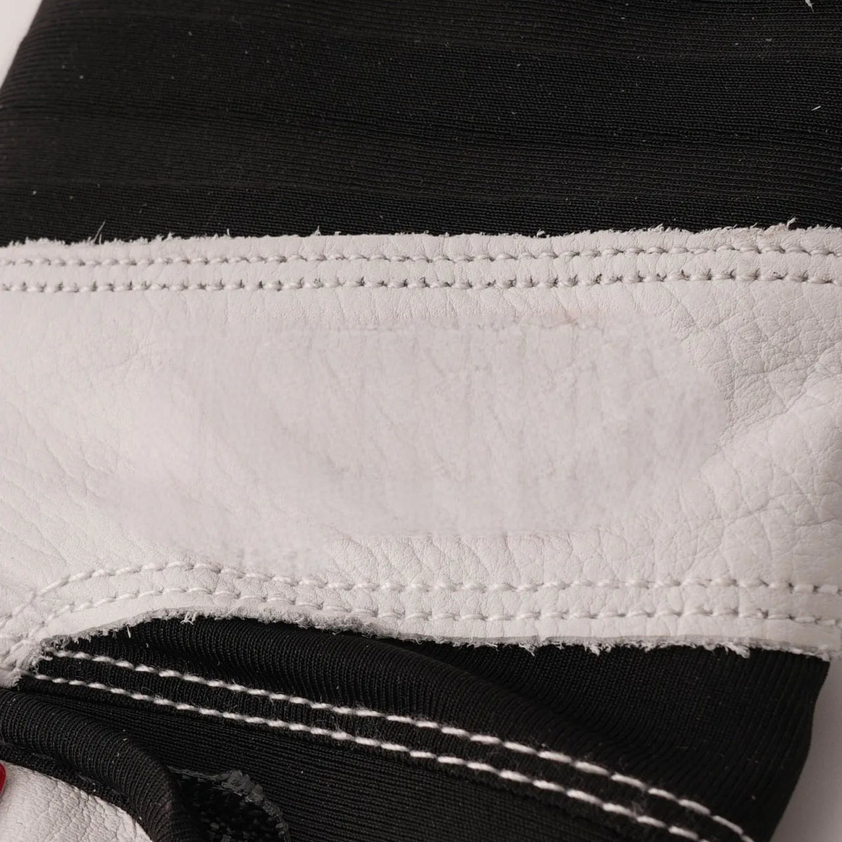 White batting glove cuff with textured black elastic and double-row stitching