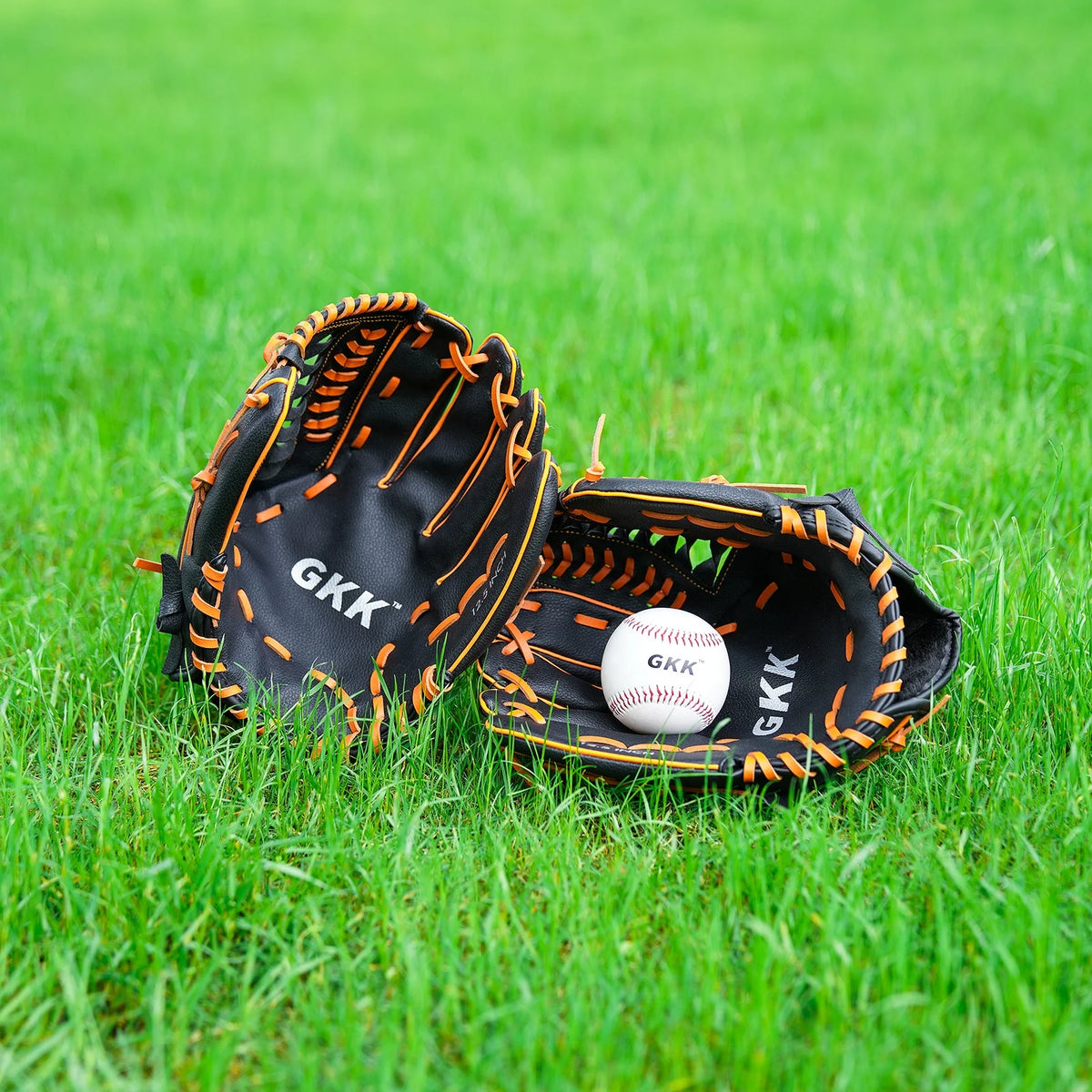 Left-handed infield baseball glove on grass, black leather with orange trim