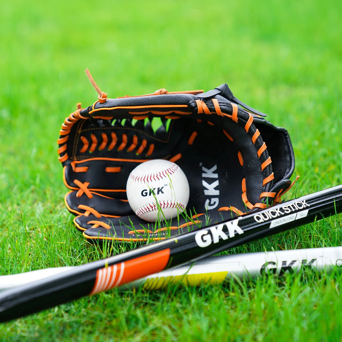 Left-handed infield baseball glove on grass, black leather with orange lacing