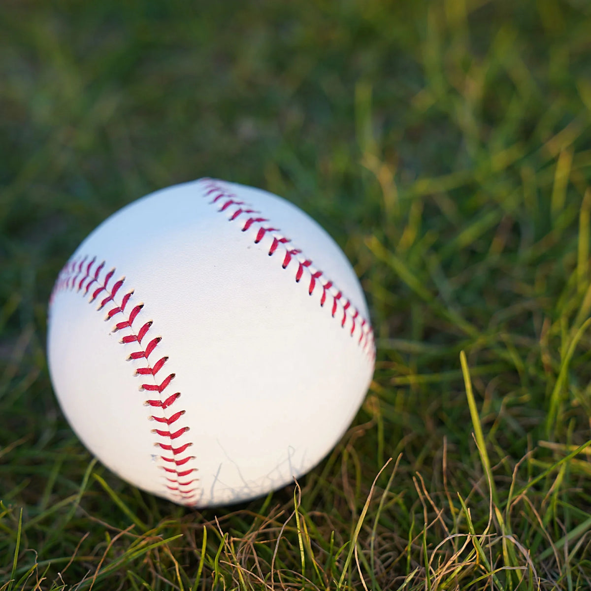 White baseball with red stitched seam close-up on grass