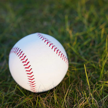 White baseball with red stitched seam close-up on grass